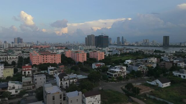 Smooth drone orbit revealing the Da Nang skyline, modern bridge and urban landscape during the golden sunrise in Vietnam.