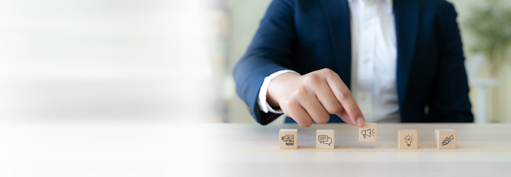 Education marketing strategy and content planning concpt. A businessman arranges education marketing icons. Content strategy, communication, online learning, audience engagement and business growth.