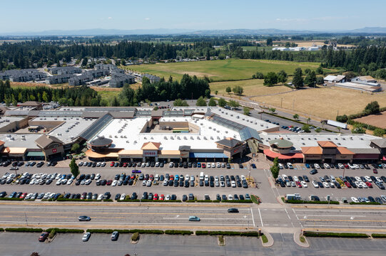 Aerial drone photo of a busy outlet shopping center in Woodburn, Oregon, USA during the Juneteenth holiday with crowded parking lots, retail stores, and shoppers on a clear summer day