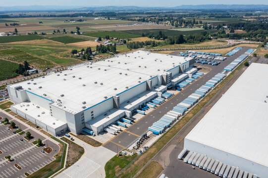 Woodburn, Oregon, USA - June 19, 2026 - Aerial drone photo of Amazon Fulfillment Center PDX8 with warehouse buildings, loading docks, trailers and logistics operations