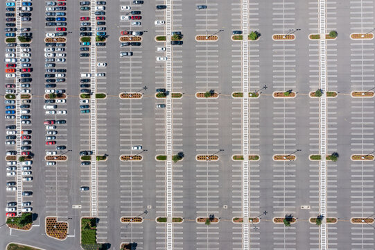 Aerial drone photo of a large commercial parking lot with parked cars beside an industrial warehouse and distribution facility in Woodburn, Oregon, USA on a clear summer day