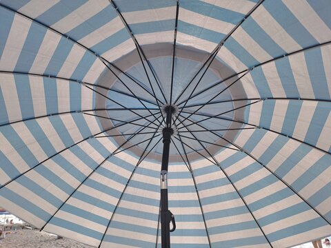  Under the parasol view on a sunny day. Summer vacation, sun protection and beach holiday background concept.