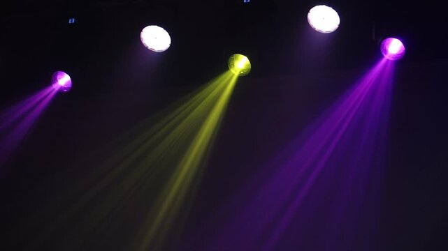 Bright theatrical spotlights shining through atmospheric haze, dynamically changing colors from crisp white to warm orange in a dark event venue.
