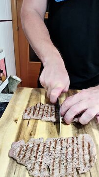 Slicing grilled beef steaks on wooden board for healthy high protein homemade dinner