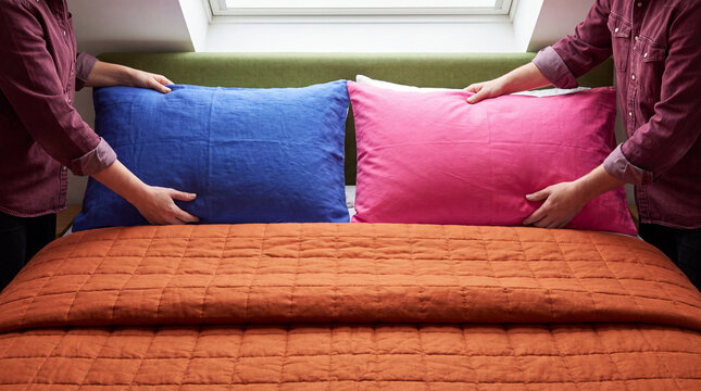 Hands settle colorful pillows in a restful bedroom routine