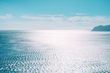 Peaceful ocean horizon under a bright blue sky with shimmering sunlight reflecting on gentle waves, offering a calming seascape for travel and relaxation themes. © Hasbi