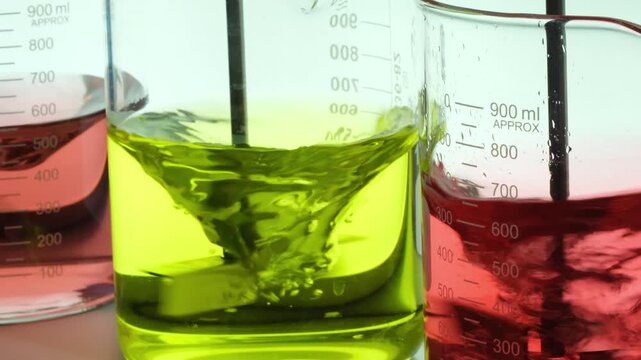 Liquid mixing in glass beaker for science experiment. Close up.  Analytical laboratory.  Mixing of solution. Laboratory Mixer.