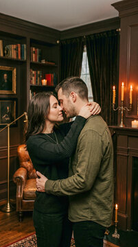 Abrazo apasionado y rom&aacute;ntico de una pareja a la luz de las velas en un ambiente elegante, tenue y lleno de sensualidad de buen gusto.