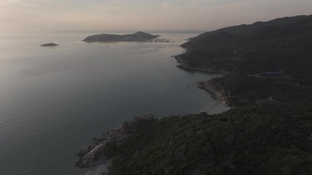 Aerial drone footage of sunrise over Binh Hung Island and its stunning coastline in Khanh Hoa, Vietnam, featuring turquoise waters, rocky shores and breathtaking tropical seascapes.