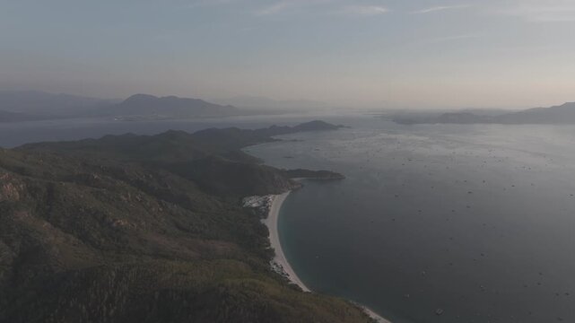 Aerial drone footage of sunrise over Binh Hung Island and its stunning coastline in Khanh Hoa, Vietnam, featuring turquoise waters, rocky shores and breathtaking tropical seascapes.