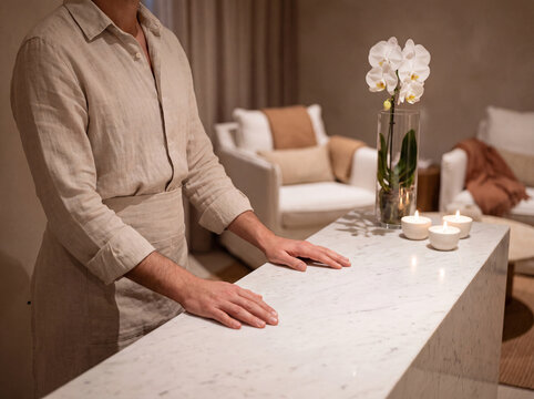 Quiet hotel spa reception area with a host behind a low marble desk and a single orchid on the surface