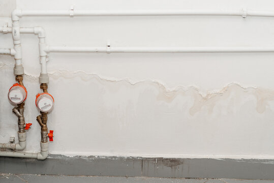streaks of water on white wall and two water meters, consequences of flooding, water supply accident, sewer breakout, need for repairs