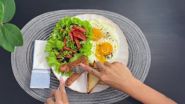 High angle footage of hand holding a fork and taking food from a breakfast plate. Concept of morning routine, eating process, tasty breakfast, food blog, morning meal, and lifestyle video. Real-time m