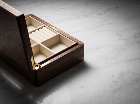 Open wooden jewelry box on marble surface