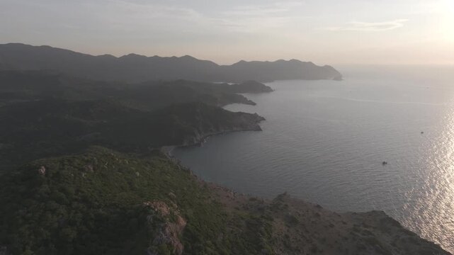 Aerial drone footage of sunrise at Hang Rai, Khanh Hoa, Vietnam, featuring dramatic rocky coastline, turquoise sea, coral reef, golden morning light and breathtaking coastal landscape.