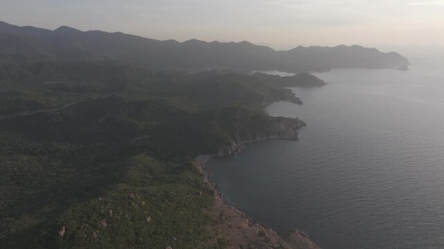 Aerial drone footage of sunrise at Hang Rai, Khanh Hoa, Vietnam, featuring dramatic rocky coastline, turquoise sea, coral reef, golden morning light and breathtaking coastal landscape.