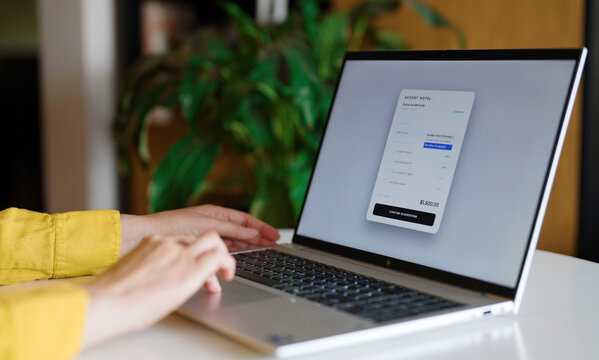 Woman using laptop to book hotel room reservation online.