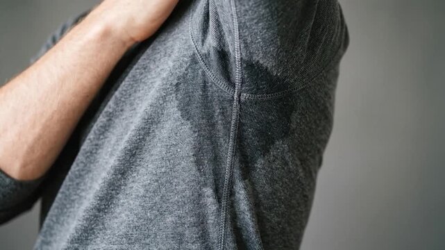 Wet sweat stain under armpit of a man wearing grey shirt