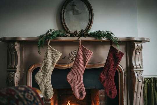 Cozy Christmas stockings hanging on mantel above fireplace, knitted and textured holiday decor in warm light for winter home celebration