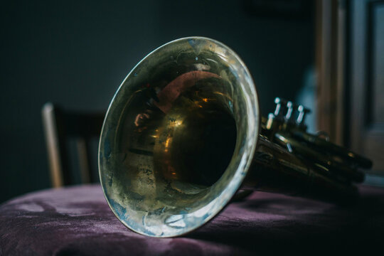 Close-up of vintage brass horn and glass lens on table in dim light, antique music instrument detail with warm reflections for editorial design