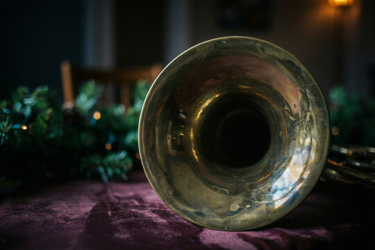 Close-up of vintage brass trumpet bell on dark velvet table, moody warm lighting with soft bokeh background, jazz music concept for posters