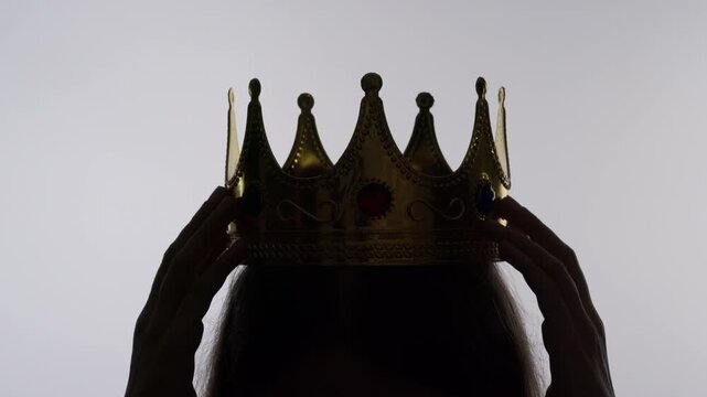 Woman putting royal crown on her head. Concept of luxury accessory symbolizing success, power and leadership.