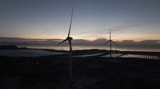 Solar panels and wind turbines in Phuoc Dinh, Khanh Hoa ( Ninh Thuan ) Vietnam. Aerial view of green energy hybrid farm, renewable power generation, and sustainable landscape.