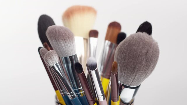 Close-up of various professional makeup brushes standing in a organizer container. Isolated on white background for beauty and cosmetics concepts.