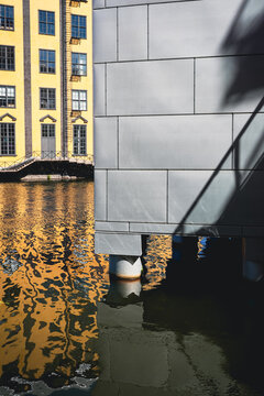 Modern grey facade and yellow building reflection in water