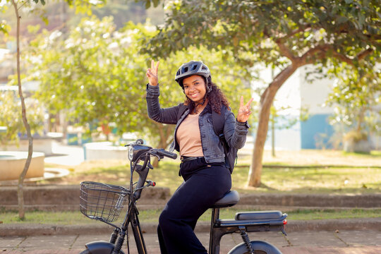 Smiling young Black Brazilian woman on an electric bicycle, representing urban mobility, everyday commuting, and sustainable transportation.
