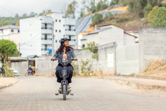 Young Black Brazilian woman riding an electric bicycle during her daily commute, representing modern urban mobility, practical transportation, and sustainable mobility.