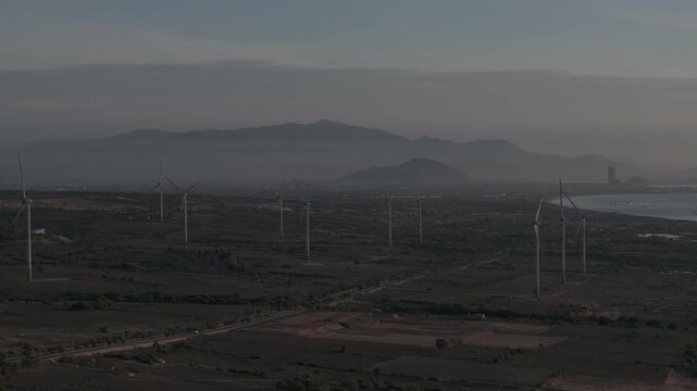 Aerial drone footage of Wind Farm in Phuoc Dinh, Khanh Hoa, Vietnam, featuring giant wind turbines along the coastal landscape, showcasing renewable energy, sustainable power and clean technology.