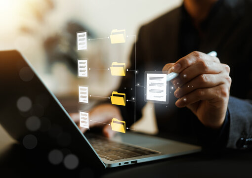 Businessman using a stylus pen organizing and managing digital document files and folders on a laptop. Concept of document management system, database storage, and corporate workflow automation.