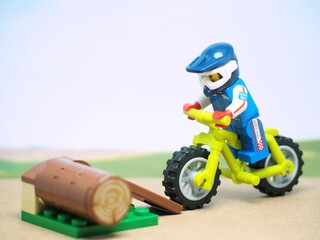 Obraz premium Indonesia - August 24, 2023 : Mini toy of action figure at outdoor with blurred background. Toy photography concept design. Minifigure of MTB rider athlete character at extreme route.
