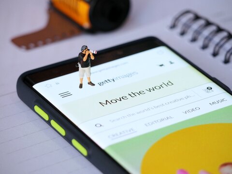 Indonesia - May 12, 2023 : View of GettyImages application on screen display of smartphone at table with mini toy figure. Background is blurred. Content Creator Mobile App concept design.