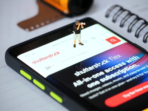 Indonesia - May 12, 2023 : View of Shutterstock application on screen display of smartphone at table. Background is blurred. Content Creator Mobile App concept design.