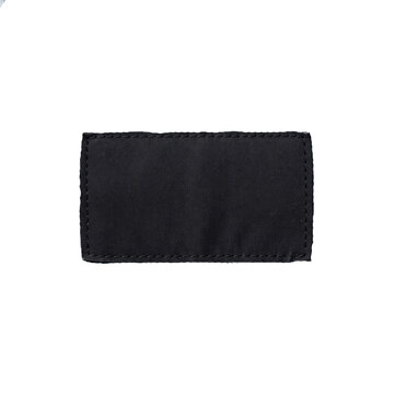 Blank black fabric tag patch sewn on dark textile background