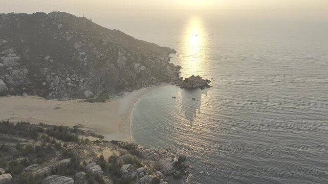Aerial drone footage of sunrise over Mui Dinh Lighthouse and pristine beach in Khanh Hoa, Vietnam, showcasing golden morning light, dramatic coastline, turquoise sea and iconic coastal landmark.