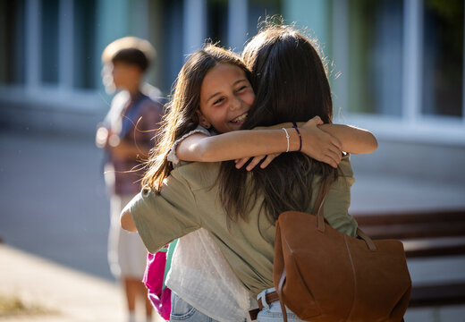 Mother greets daughter in schoolyard