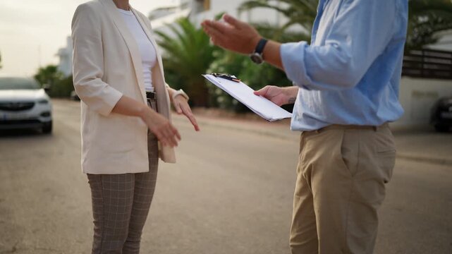 Unrecognizable businesswoman and businessman arguing outdoors as the woman refuses to sign the document, expressing disagreement with the contract terms through gestures and discussion
