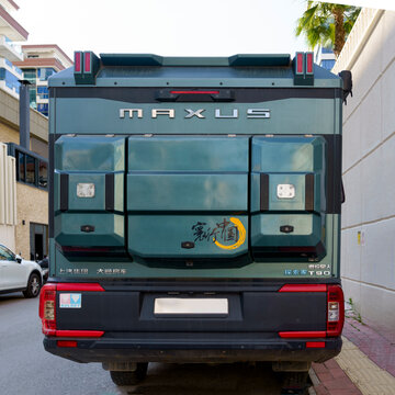 Maxus T90 truck parked on a city street, showcasing its rear design and branding with modern buildings in the background