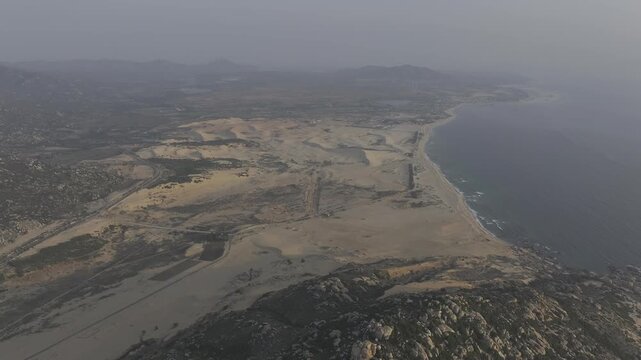 Aerial drone footage of sunrise over Mui Dinh Lighthouse and pristine beach in Khanh Hoa, Vietnam, showcasing golden morning light, dramatic coastline, turquoise sea and iconic coastal landmark.