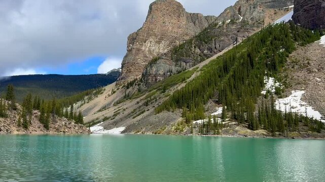 Beautiful view on the Moraine Lake in National Park of Banff, Canada. Stunning view of a mountain lake surrounded by lush green forest and rocky cliffs, showcasing the natural beauty of the landscape.