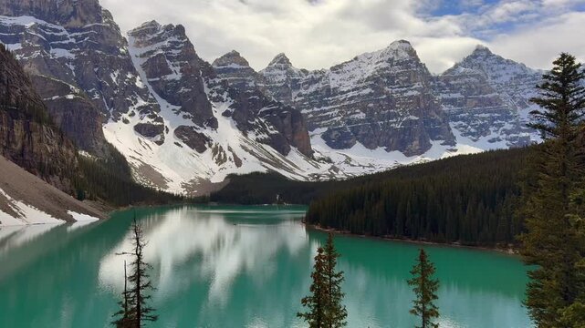 Beautiful view on the Moraine Lake in National Park of Banff, Canada. Stunning view of a mountain lake surrounded by snow-capped peaks and evergreen trees, showcasing the serene beauty of nature.