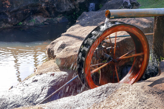 Rustic wooden water wheel operating in a traditional eco friendly hydraulic pumping system