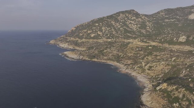 Aerial drone footage of sunrise over Mui Dinh Lighthouse and pristine beach in Khanh Hoa, Vietnam, showcasing golden morning light, dramatic coastline, turquoise sea and iconic coastal landmark.