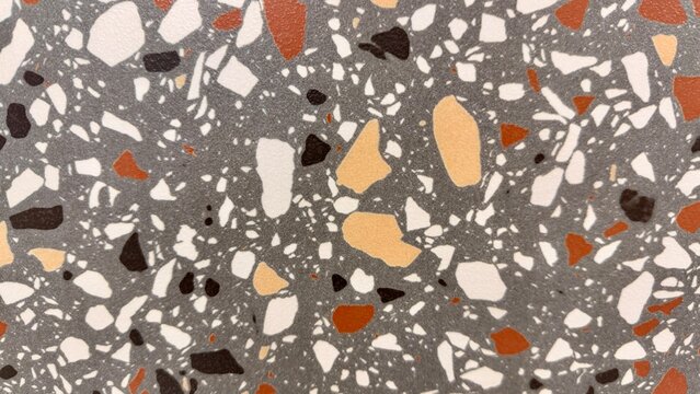 High-resolution close-up of a terrazzo-style ceramic floor tile featuring colorful natural stone fragments embedded in a grey surface