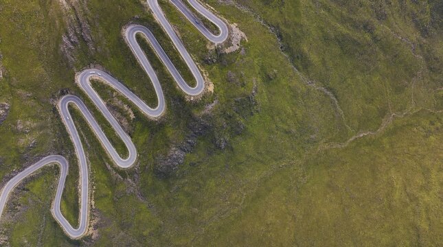 Winding road cuts through green hills on a sunny day in a rural area