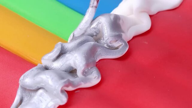 Close up of painting metallic silver glaze on cake frosting