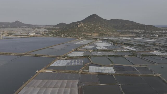 Aerial drone footage of Phuong Cuu Salt Fields in Khanh Hoa, Vietnam, showcasing traditional sea salt production, geometric salt ponds, coastal landscape and sustainable local industry.